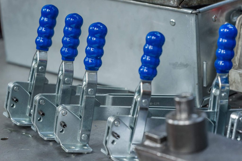 A line of blue handles on Toggle clamps of various sizes manufactured by Sandfield Engineering